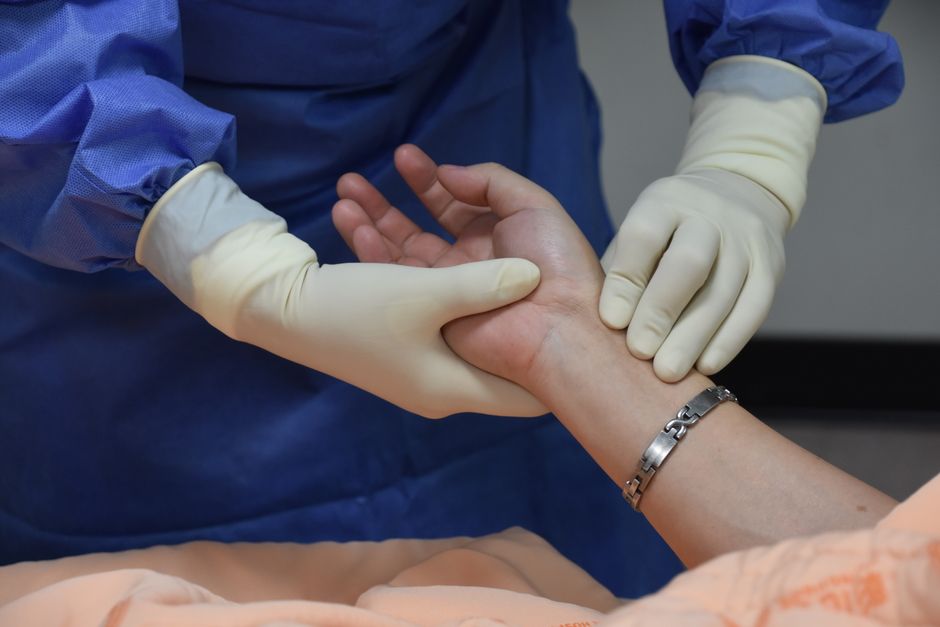 A clinician examining a patient's hand during a consultation