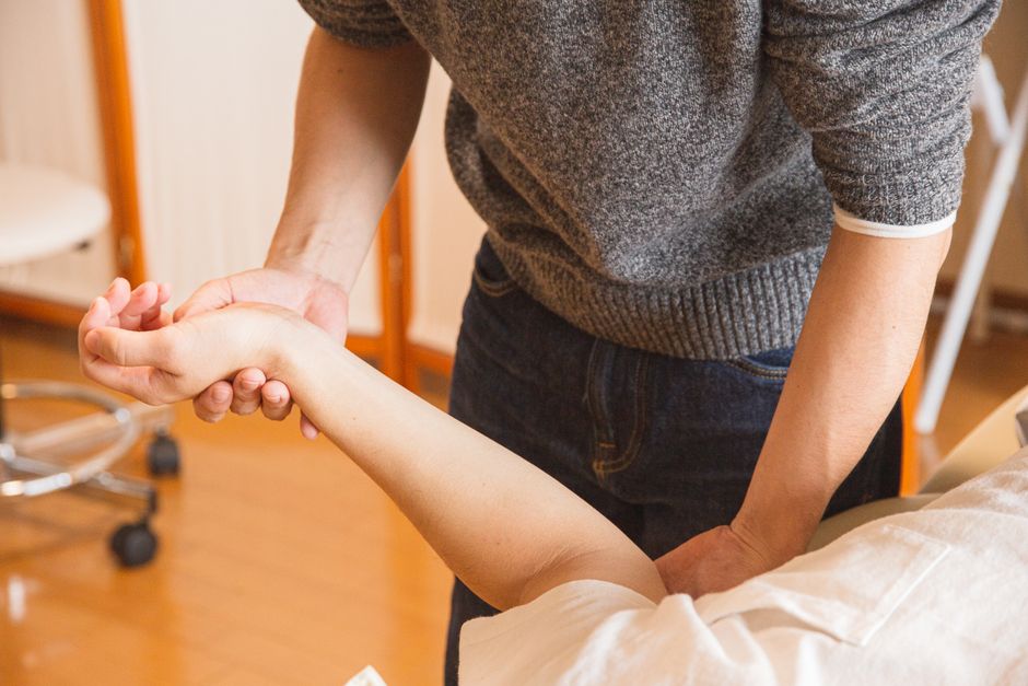 A clinician gently supporting a patient's wrist during a hand exam